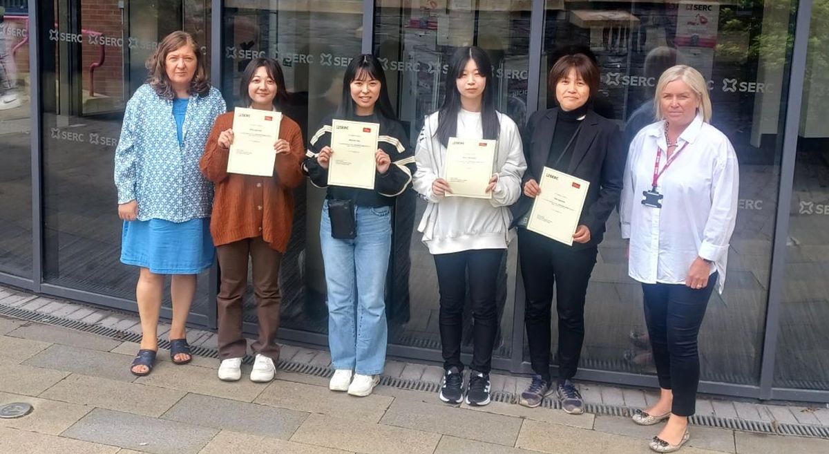 Group of six women, four holding certificates, pictured outside SERC's Bangor Campus